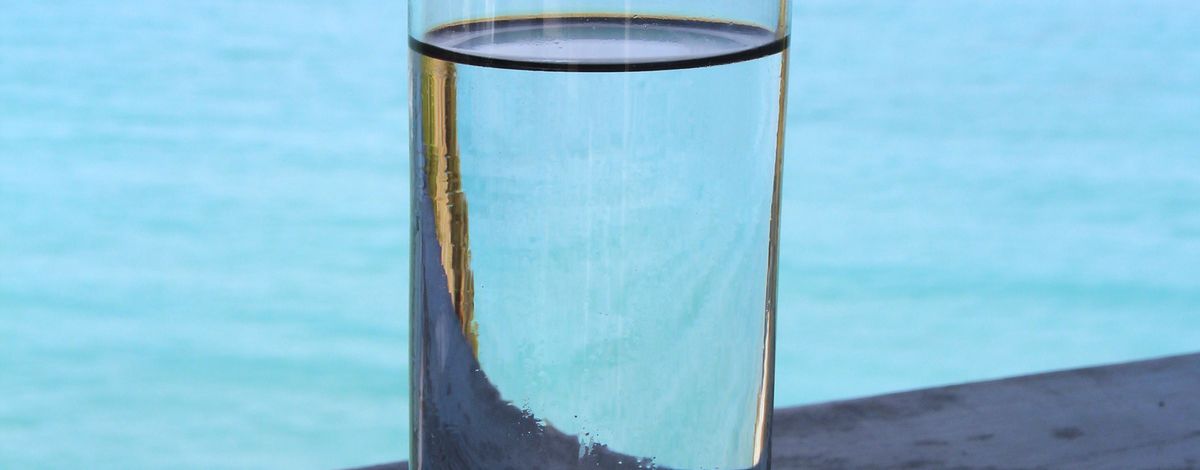 Ett glas med rent vatten vid havet